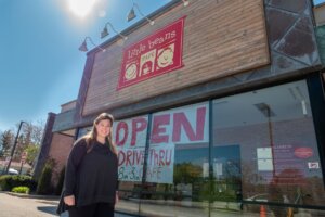 A woman poses in front of her restaurant.